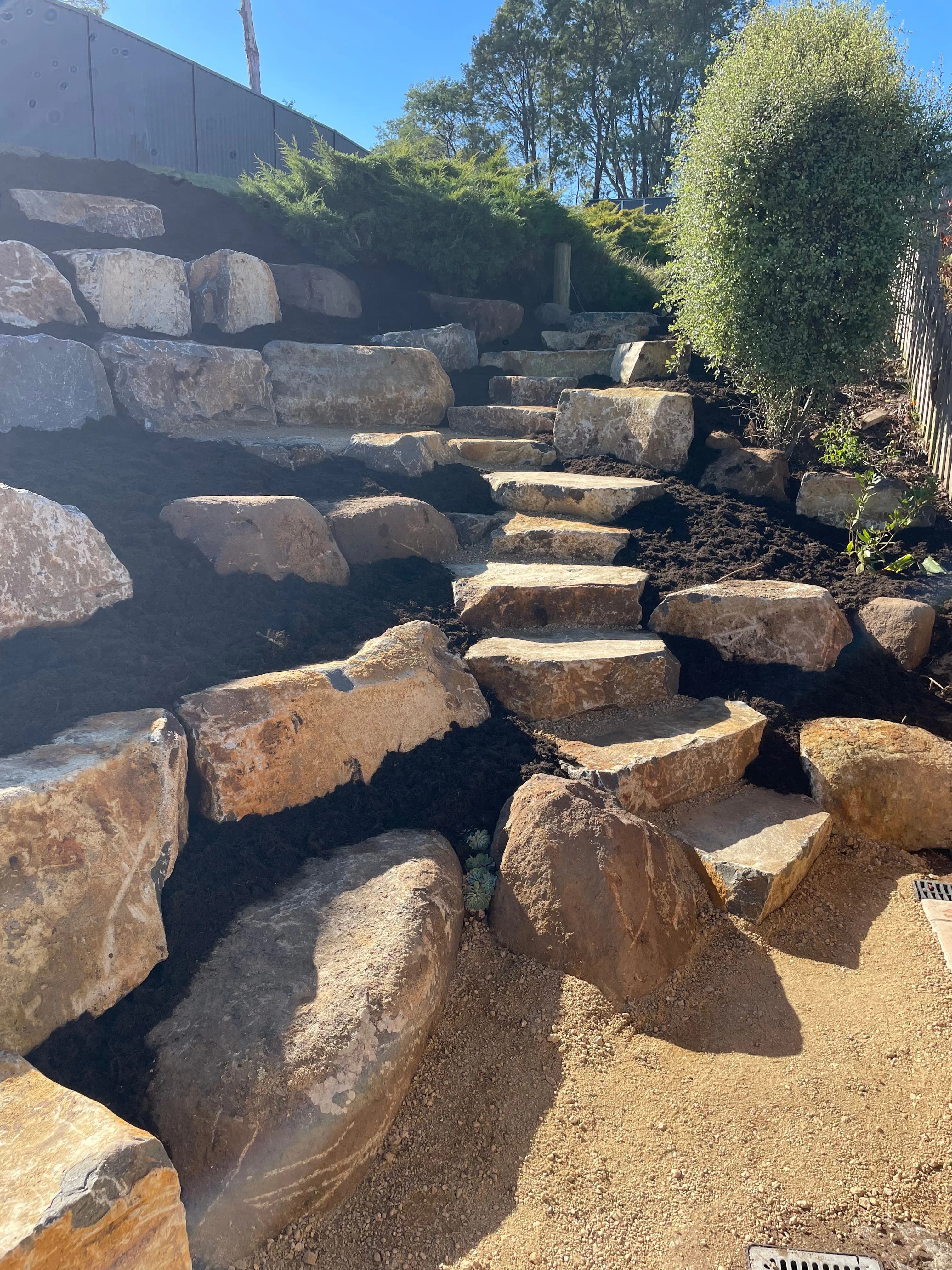 Sandstone steps and tiered retaining walls with fresh mulch and plantings